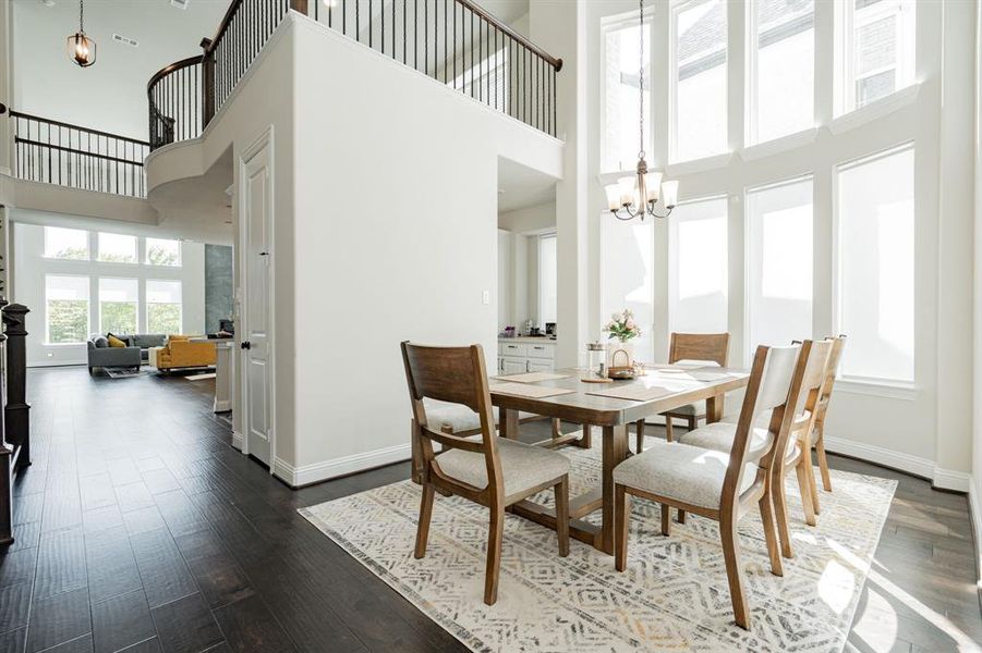 Dining space featuring dark wood-type flooring, a notable chandelier, a high ceiling, and baseboards