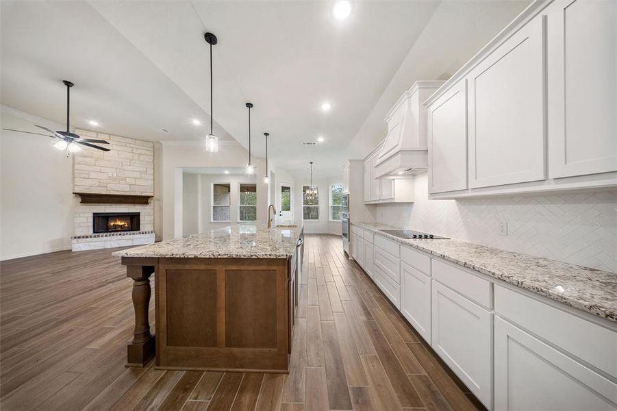 Kitchen with white cabinets, a kitchen bar, a fireplace, decorative backsplash, and recessed lighting