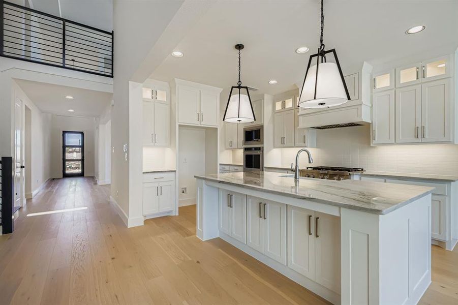 Kitchen featuring glass insert cabinets, white cabinets, light stone counters, decorative backsplash, and recessed lighting Kitchen featuring glass insert cabinets, white cabinets, light stone counters, decorative backsplash, and recessed lighting