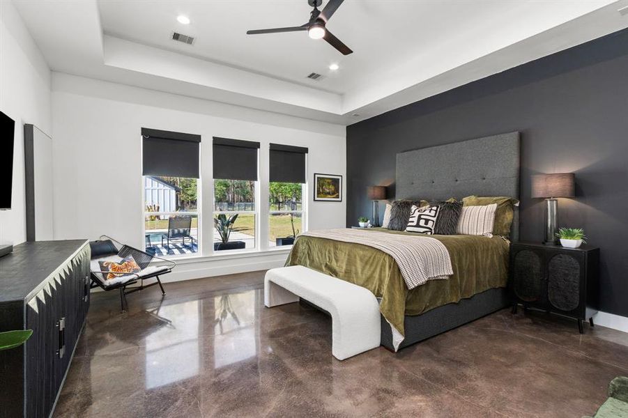 The large primary bedroom with recessed ceilings and dream views of the pool and forest surroundings.