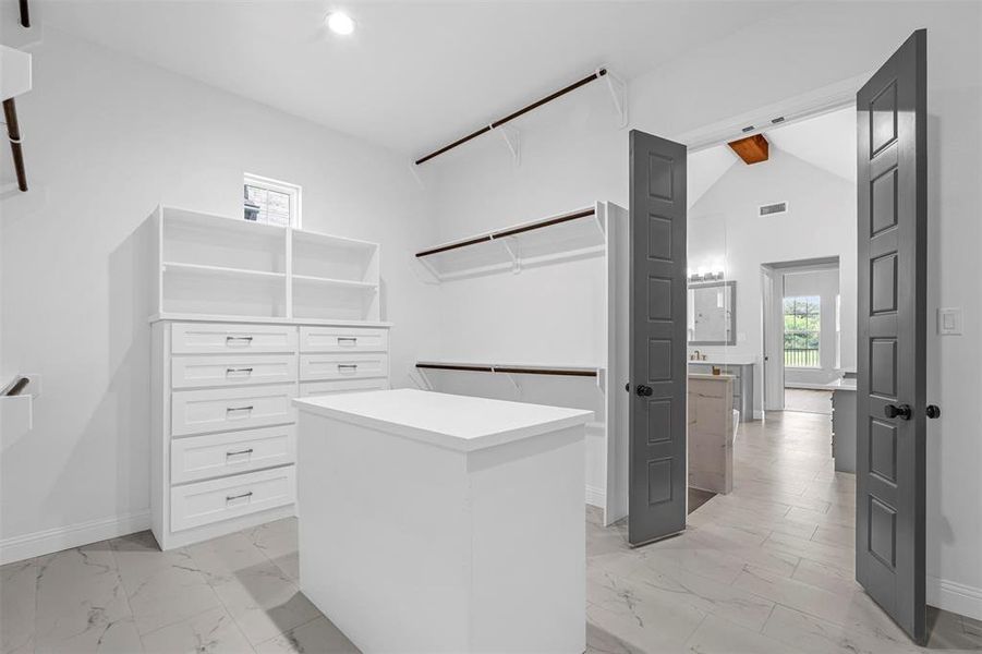 Spacious closet with lofted ceiling with beams and light tile floors