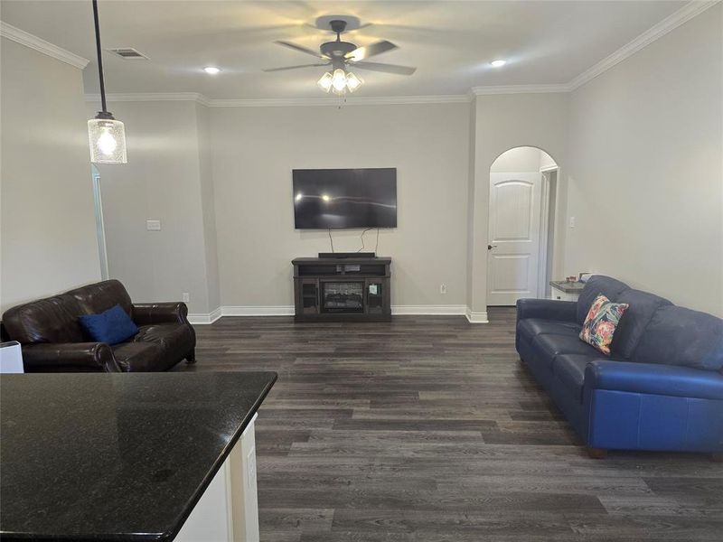 Living room featuring ceiling fan, dark hardwood / wood-style floors, and crown molding