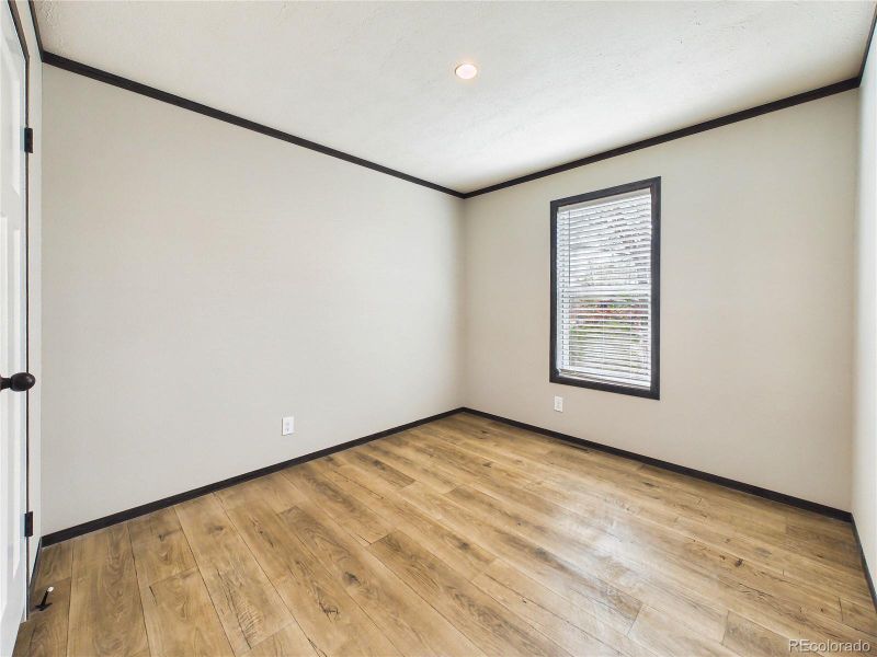 Bedroom 2 – Bright and versatile bedroom with wide-plank flooring, neutral tones, and a window that brings in natural light.