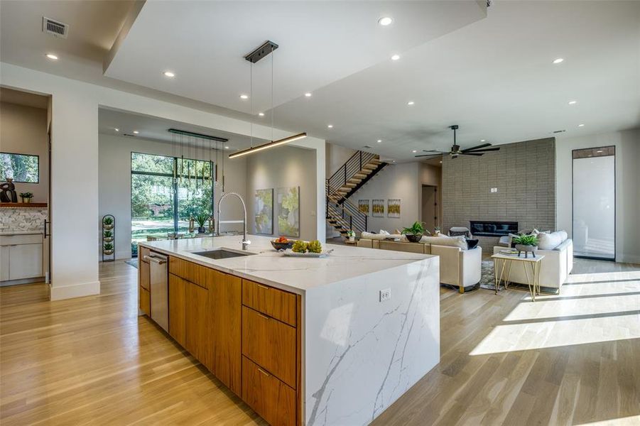 Kitchen featuring a large fireplace, light stone counters, sink, a large island, and ceiling fan