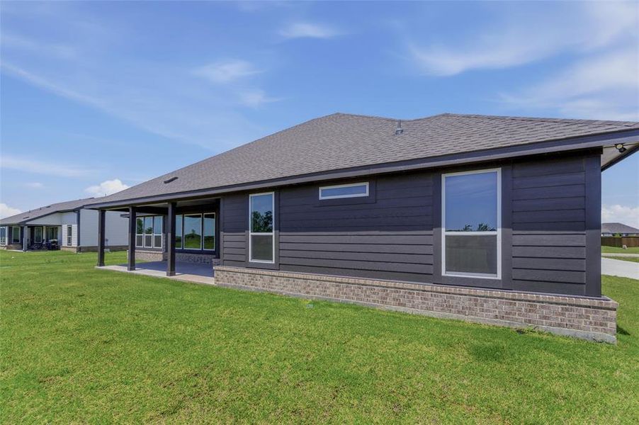 Rear exterior featuring dark horizontal siding, brick wainscoting, and a covered patio Rear exterior featuring dark horizontal siding, brick wainscoting, and a covered patio