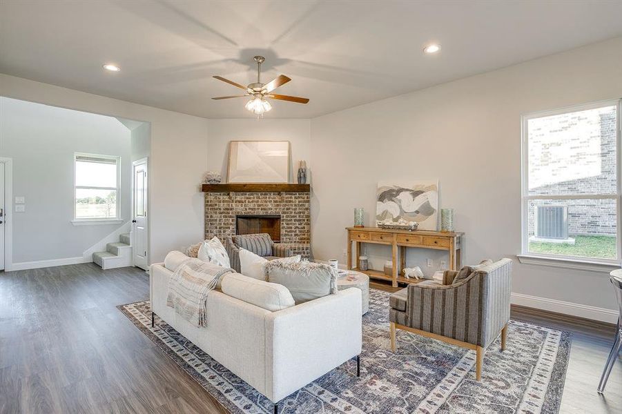 Living room with recessed lighting, wood finished floors, a fireplace, ceiling fan, and stairs