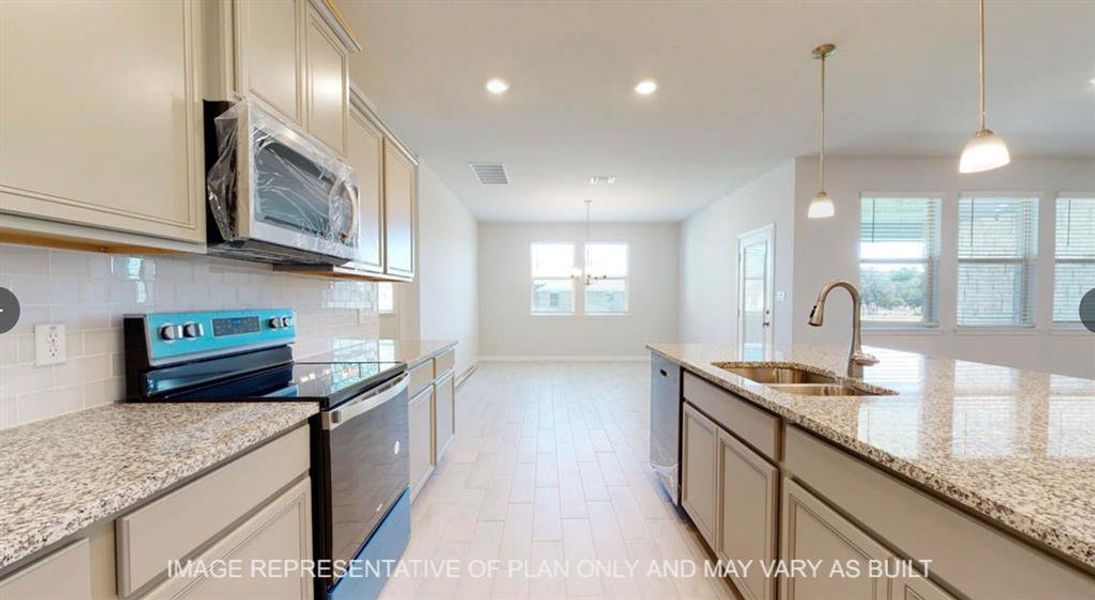 Kitchen featuring tasteful backsplash, an inviting chandelier, stainless steel appliances, a sink, and baseboards Kitchen featuring tasteful backsplash, an inviting chandelier, stainless steel appliances, a sink, and baseboards