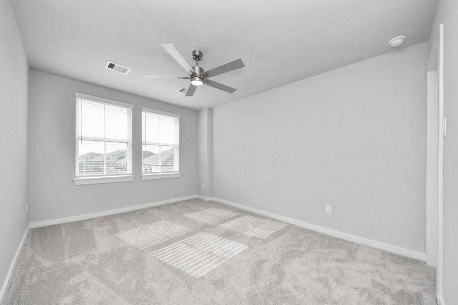 Secondary bedroom features plush carpeting, large windows that let in plenty of natural light, bright paint, and spacious closets.