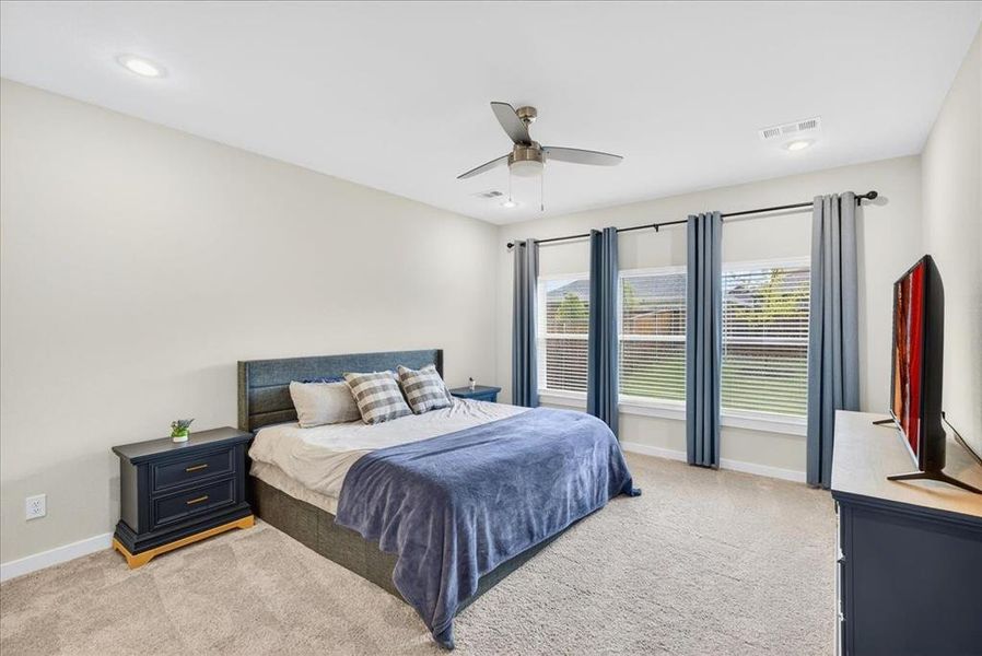 Bedroom with light colored carpet, ceiling fan, and recessed lighting