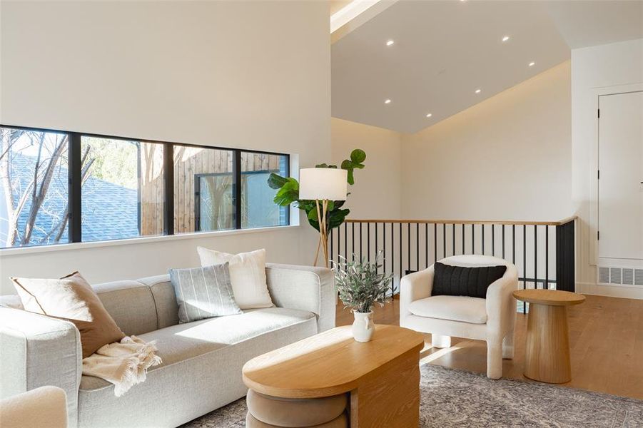 Living room with a towering ceiling and hardwood / wood-style floors