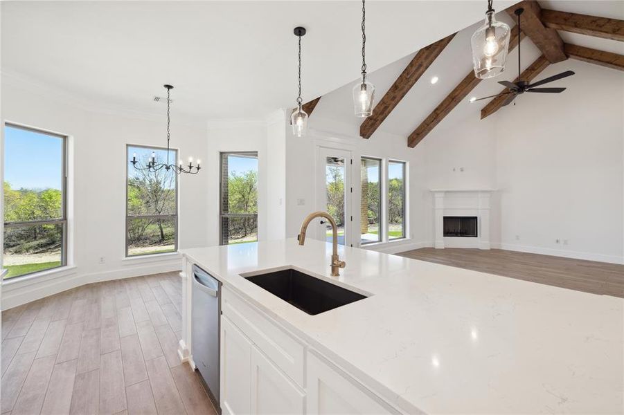 Kitchen featuring lofted ceiling with beams, sink, hanging light fixtures, light wood-type flooring, and dishwasher