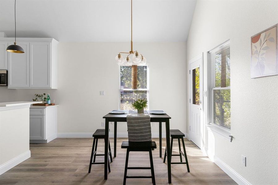 Dining area featuring an inviting chandelier, lofted ceiling, and light wood-type flooring