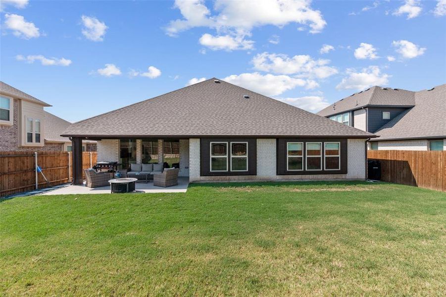 Rear view of house featuring a fenced backyard, outdoor lounge area, brick siding, a patio, and a shingled roof