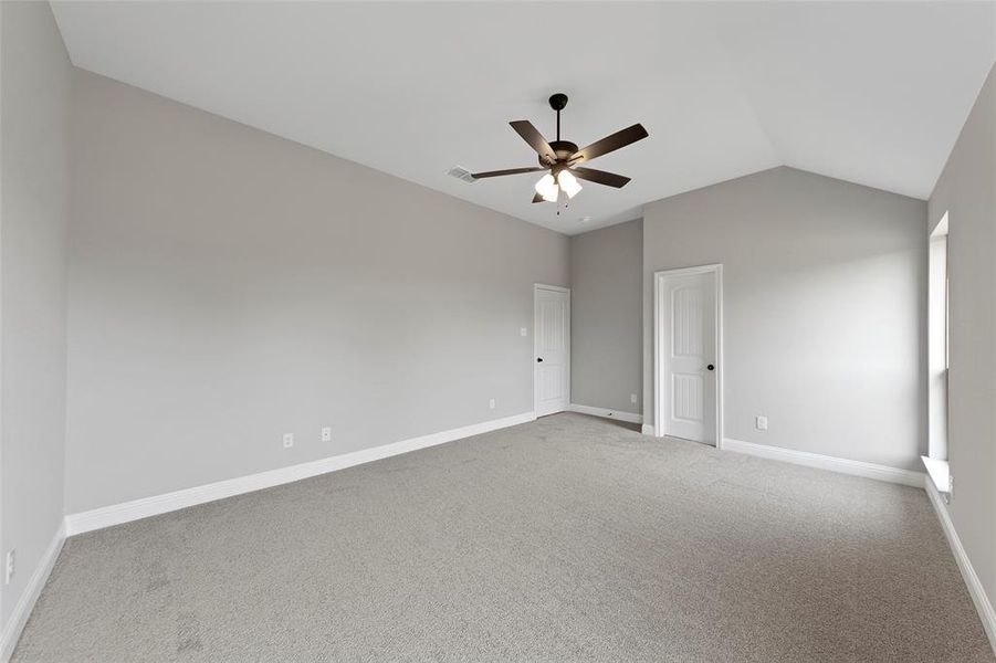 Empty room featuring carpet floors, vaulted ceiling, and ceiling fan