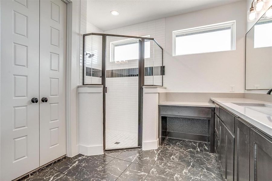 Bathroom with tile patterned floors, vanity, a shower with door, and a wealth of natural light