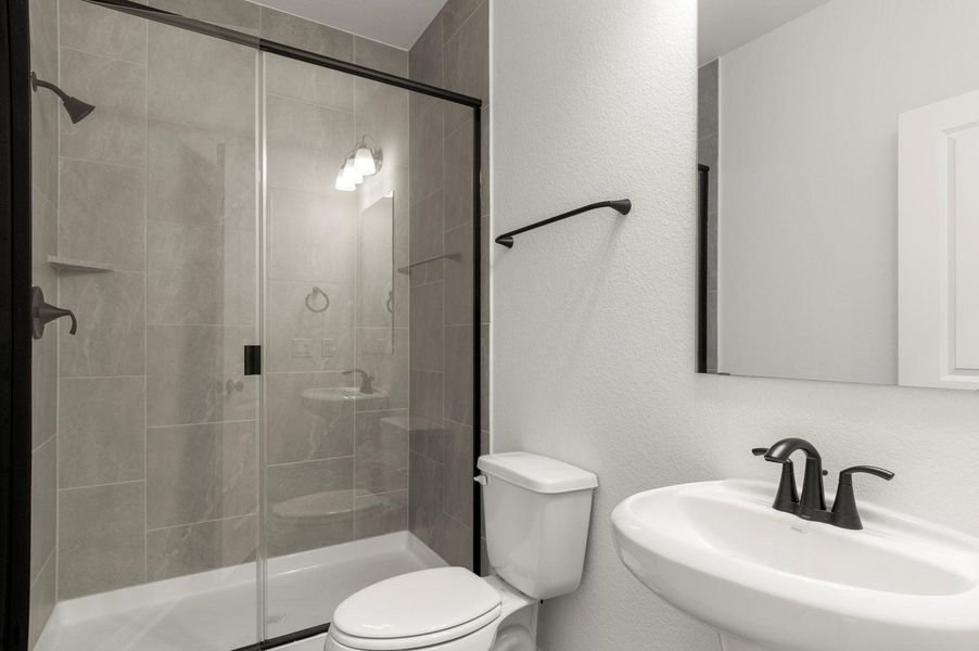 Bathroom featuring a textured wall and a stall shower