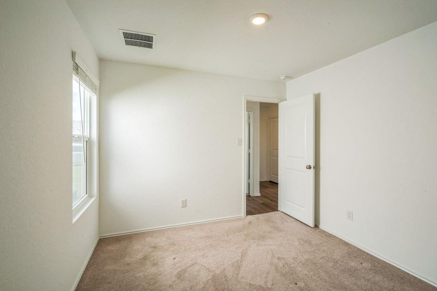 A well-lit bedroom with soft carpeting and a window offers a peaceful retreat. A well-lit bedroom with soft carpeting and a window offers a peaceful retreat.