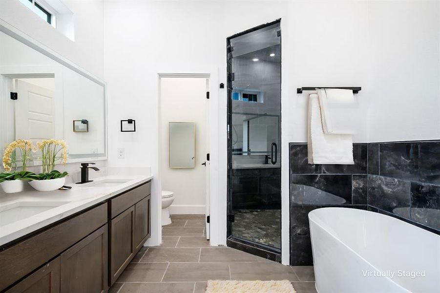 Primary Bathroom freestanding bath, a shower stall, double vanity, tile walls, and light tile patterned flooring