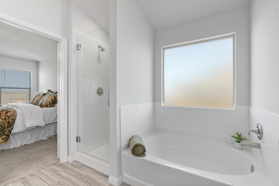 Full bath featuring a stall shower, ensuite bath, a bath, light wood-type flooring, and plenty of natural light