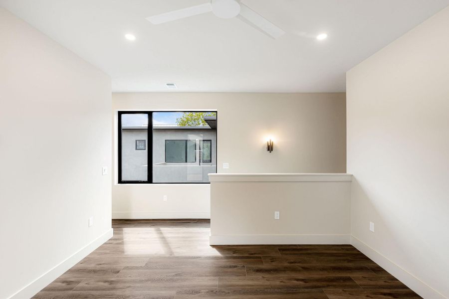 Empty room with dark wood-type flooring and recessed lighting