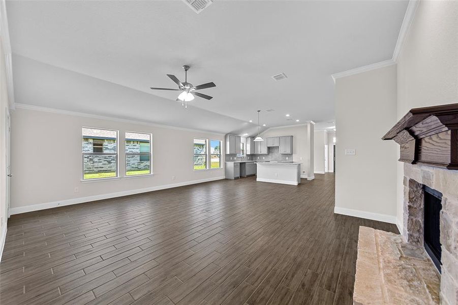 Unfurnished living room featuring dark wood-type flooring, crown molding, and ceiling fan