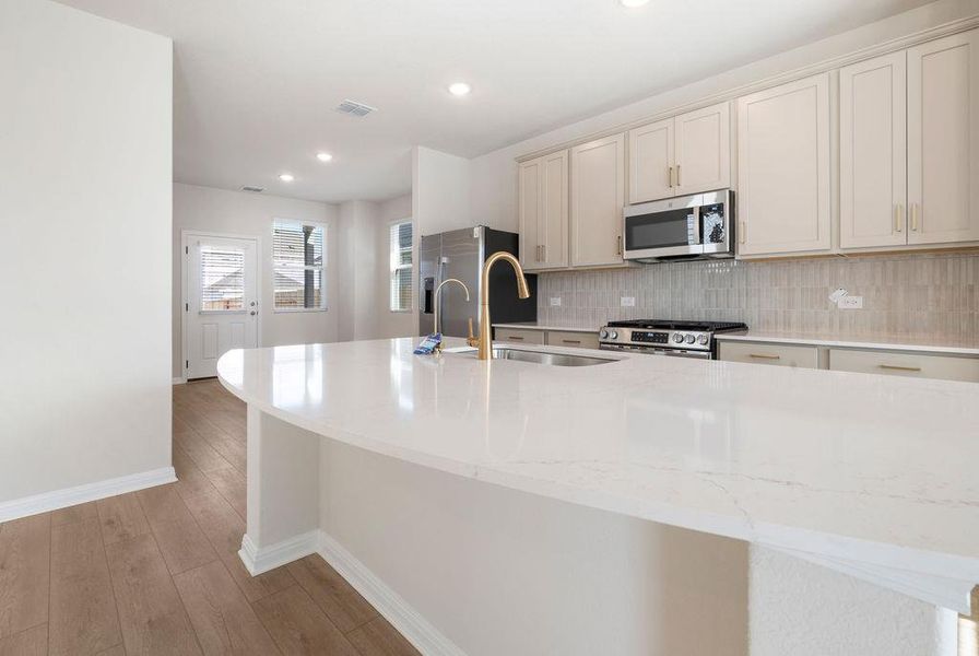 Kitchen featuring tasteful backsplash, stainless steel appliances, light stone counters, light wood-type flooring, and cream cabinets
