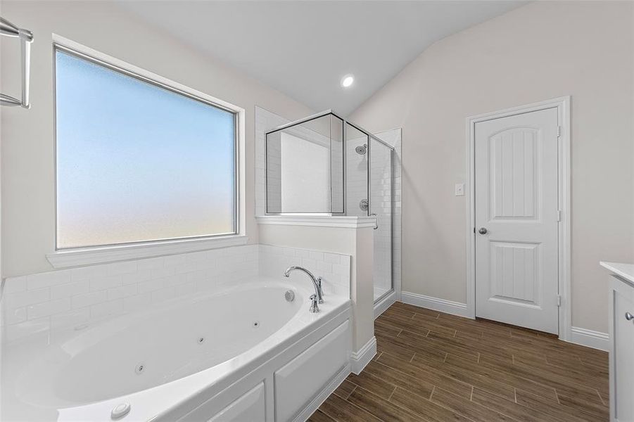 Bathroom with vanity, vaulted ceiling, and plus walk in shower