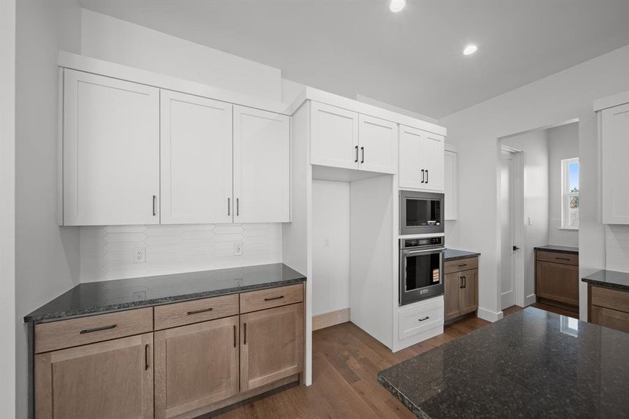 Kitchen featuring tasteful backsplash, stainless steel appliances, dark stone counters, dark wood-style flooring, and recessed lighting