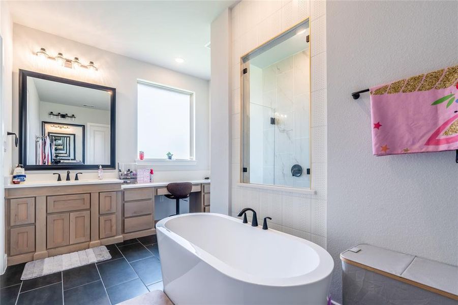Full bath with a soaking tub, vanity, dark tile patterned flooring, a textured wall, and a walk in shower