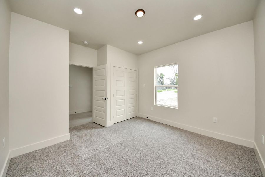 Bright and airy guest room with soft carpeting and large window