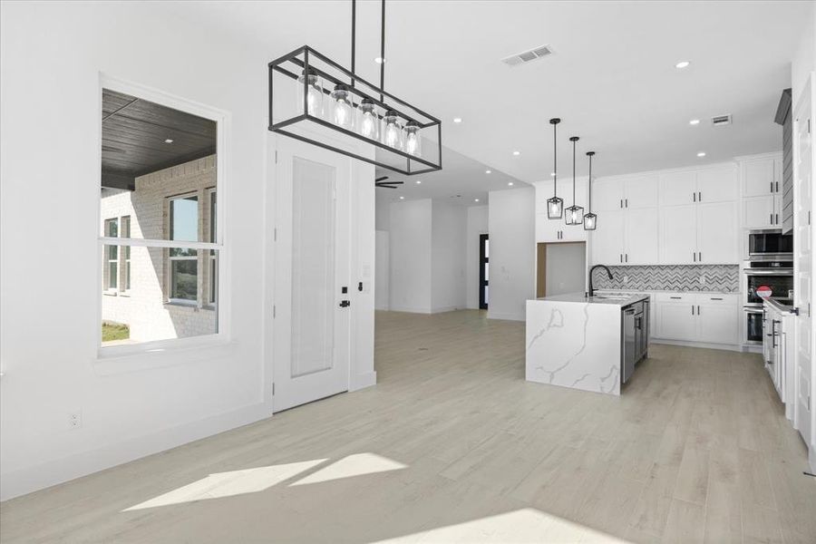 Modern kitchen featuring white cabinetry, chevron pattern tile backsplash, and a waterfall-edge island with built-in wine refrigerator