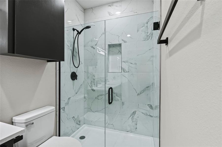 Bathroom featuring vanity, a shower with shower door, and toilet