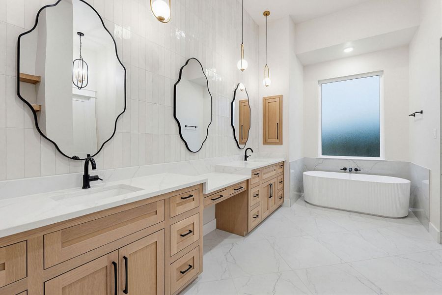 Spacious bath featuring a freestanding fluted tub, dual wood-finish vanities with light countertops, and stylish black-framed scalloped mirrors