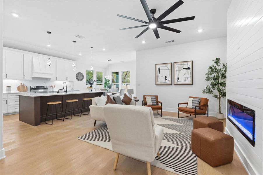 Living area with light wood-type flooring, a ceiling fan, and recessed lighting