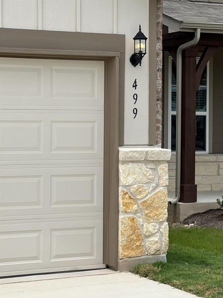 A well-appointed garage entrance features stylish stone accents and a classic wall-mounted light fixture.