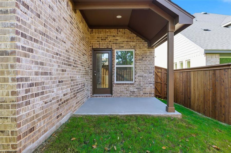 Entrance to property featuring brick siding and a patio