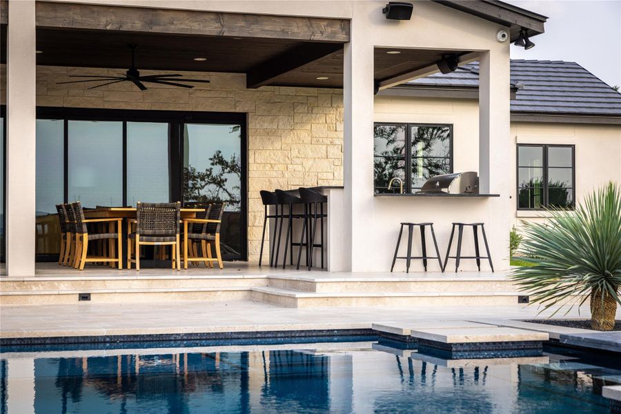 View of pool featuring ceiling fan, area for grilling, an outdoor bar, and a patio area