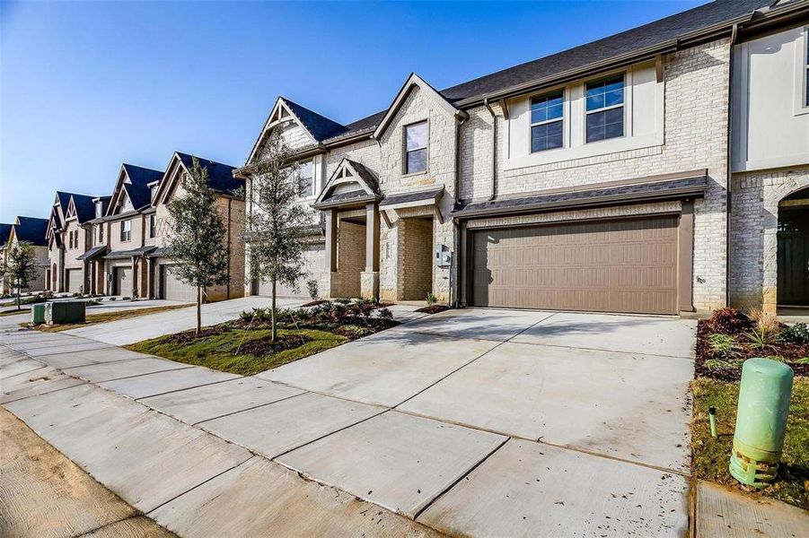 View of front of house with a garage, concrete driveway, brick siding, a residential view, and stone siding View of front of house with a garage, concrete driveway, brick siding, a residential view, and stone siding
