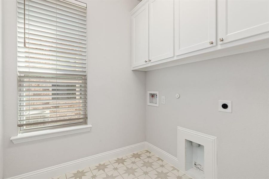 Laundry room with built in cabinets, decorative tile flooring and window