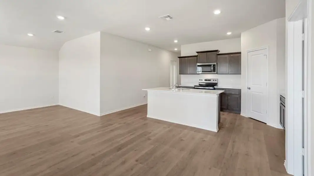Open-concept living space featuring wood-finish flooring, recessed lighting, and a kitchen island with seating