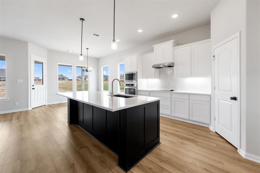 Kitchen with dark cabinetry, white cabinets, a kitchen island with sink, a chandelier, and recessed lighting Kitchen with dark cabinetry, white cabinets, a kitchen island with sink, a chandelier, and recessed lighting