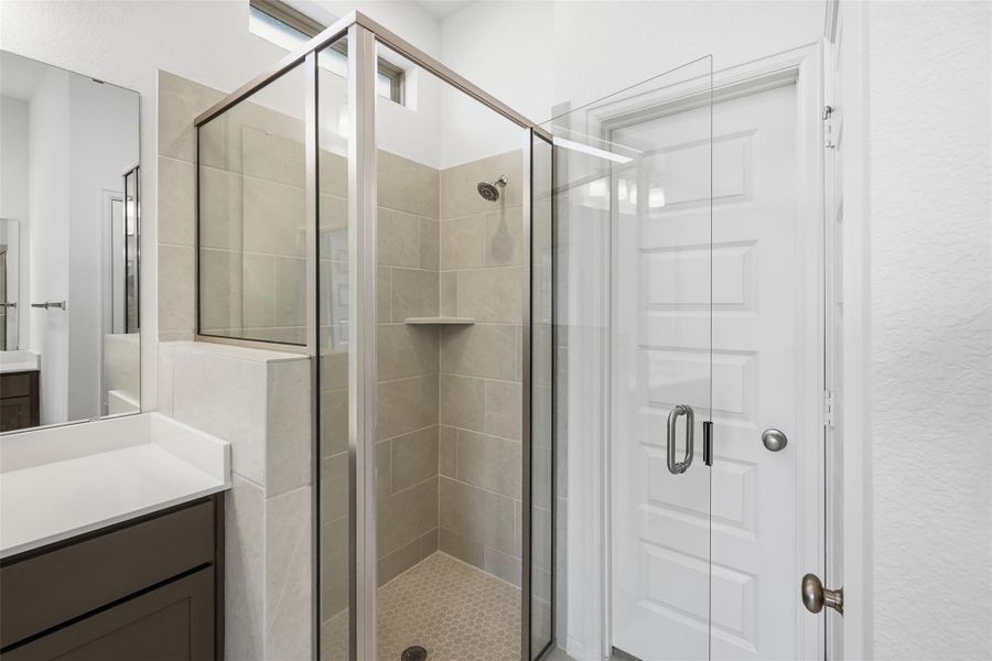 Modern bathroom with a glass-enclosed shower featuring neutral tile and a contemporary vanity, offering a clean and stylish look.