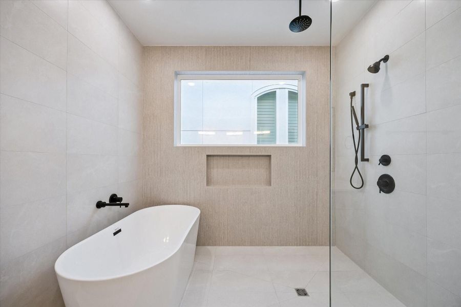 A freestanding tub is seamlessly integrated within the spacious shower area, complete with a rain shower and handheld showerhead for the ultimate in relaxation.