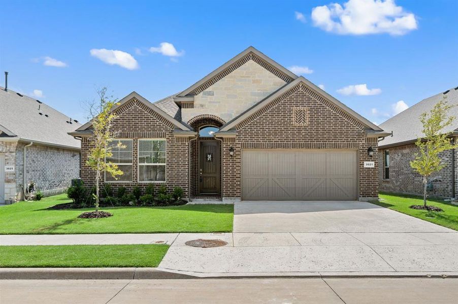 Beautiful brick-front exterior with stone accents, a welcoming covered entry, and a spacious two-car garage.