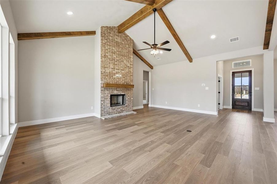 Unfurnished living room featuring light wood-type flooring, a brick fireplace, ceiling fan, and recessed lighting