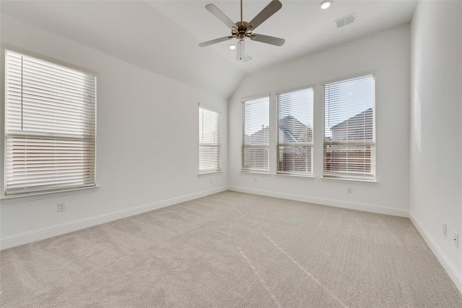 Empty room with light carpet, ceiling fan, and vaulted ceiling