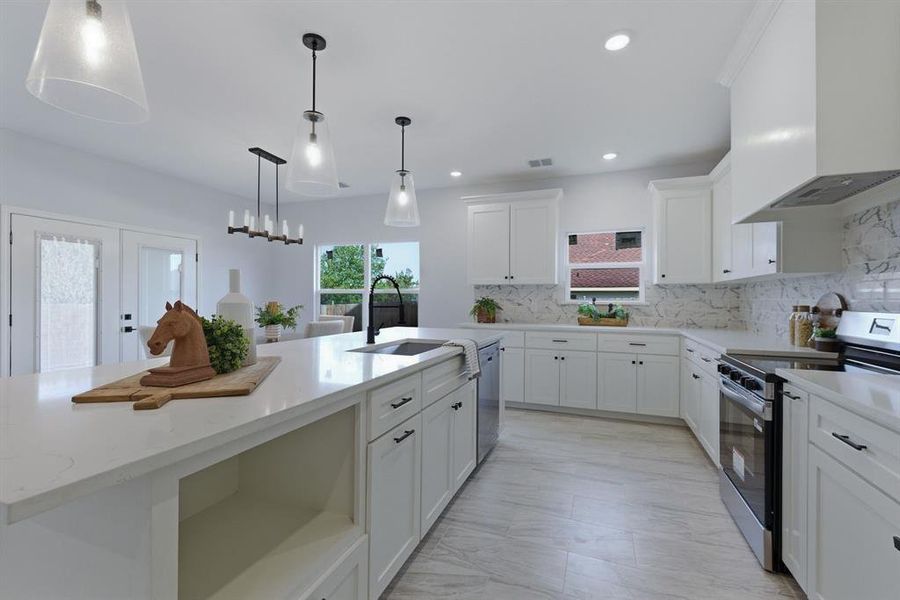 Kitchen featuring stainless steel appliances, white cabinetry, and a center island with sink Kitchen featuring stainless steel appliances, white cabinetry, and a center island with sink