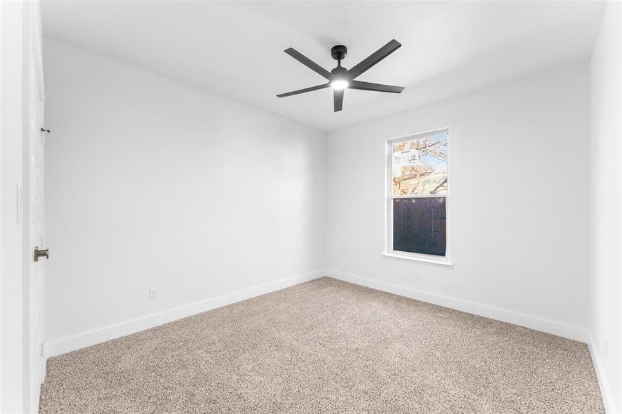 Carpeted spare room featuring baseboards and a ceiling fan