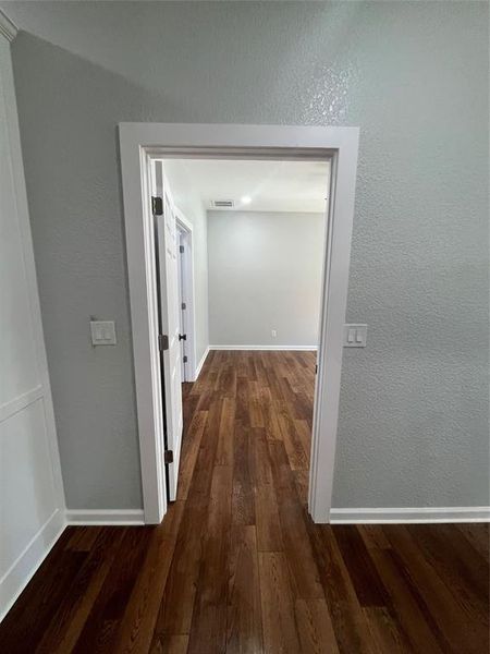 Hallway with a textured wall and dark wood-style floors Hallway with a textured wall and dark wood-style floors