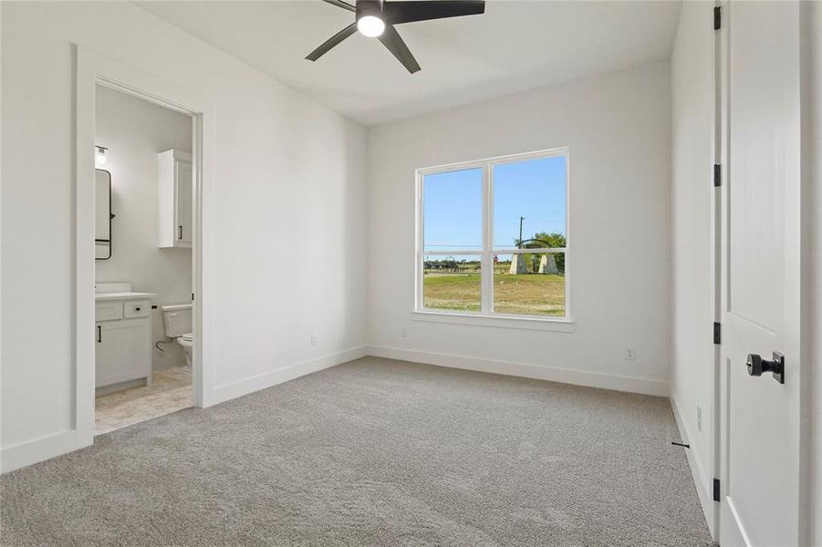 Unfurnished bedroom with light colored carpet, ceiling fan, and ensuite bath Unfurnished bedroom with light colored carpet, ceiling fan, and ensuite bath